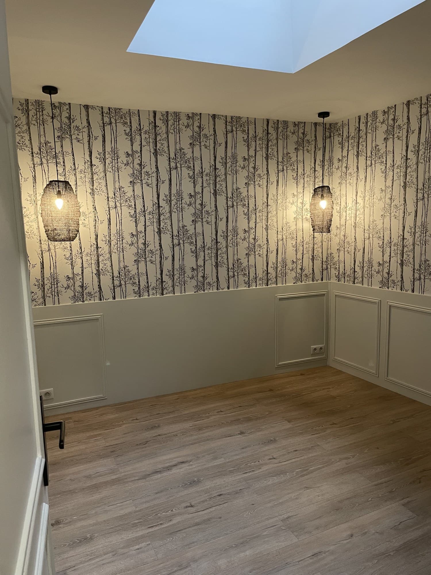 Chambre au soubassement à panneaux peint en blanc satiné, mur haut à motif de bouleaux et suspensions en fibre tressée