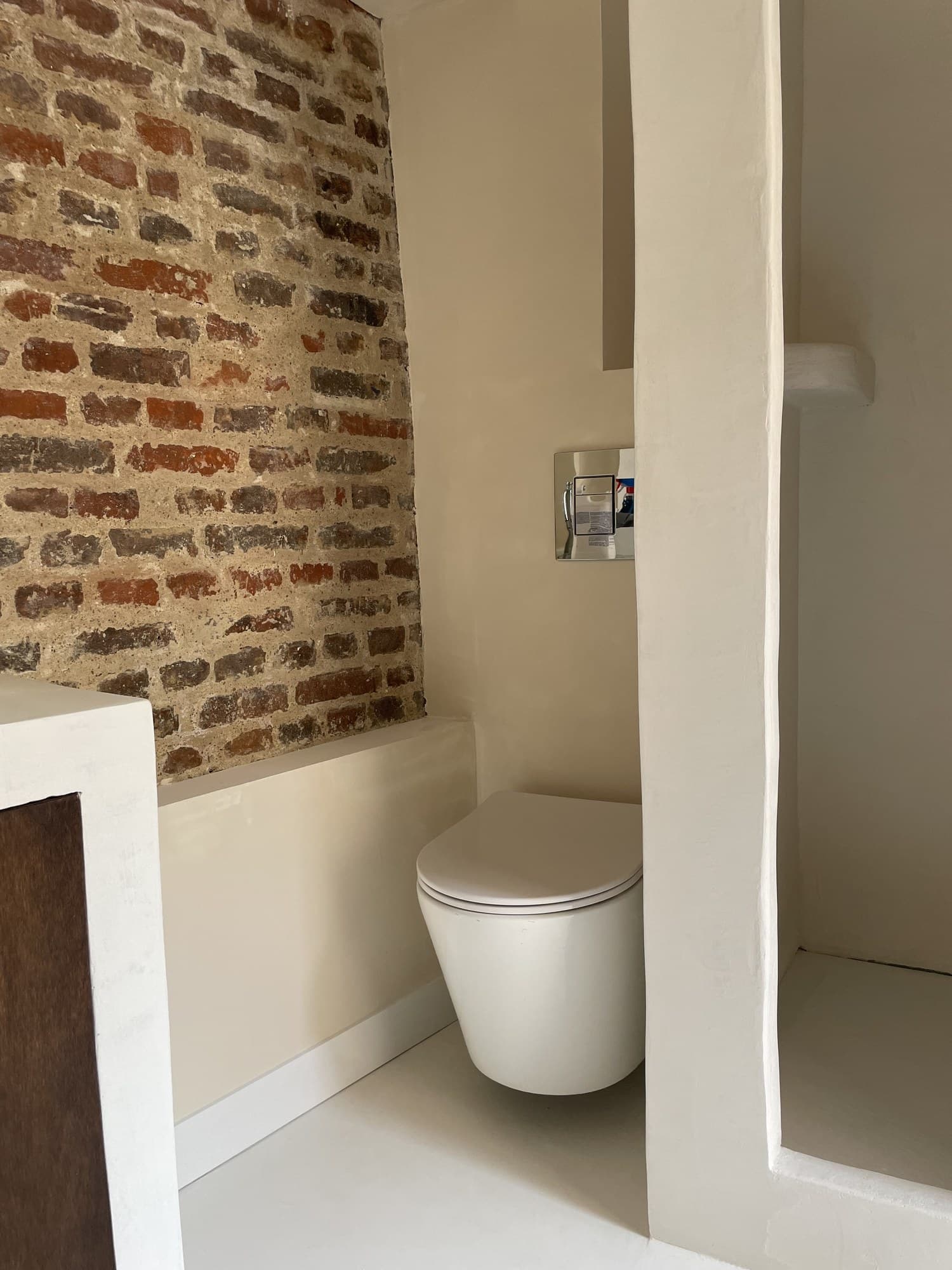 Coin toilette avec mur de brique ancienne conservé et banquette maçonnée enduite