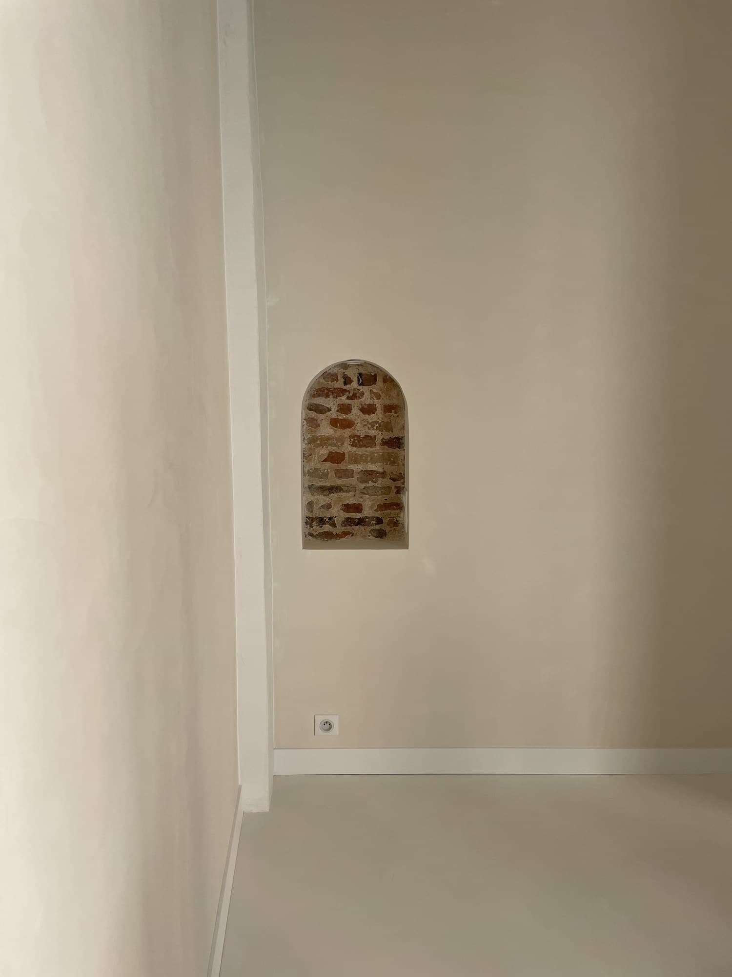 Détail d’une niche voûtée en brique dans un mur en enduit lisse