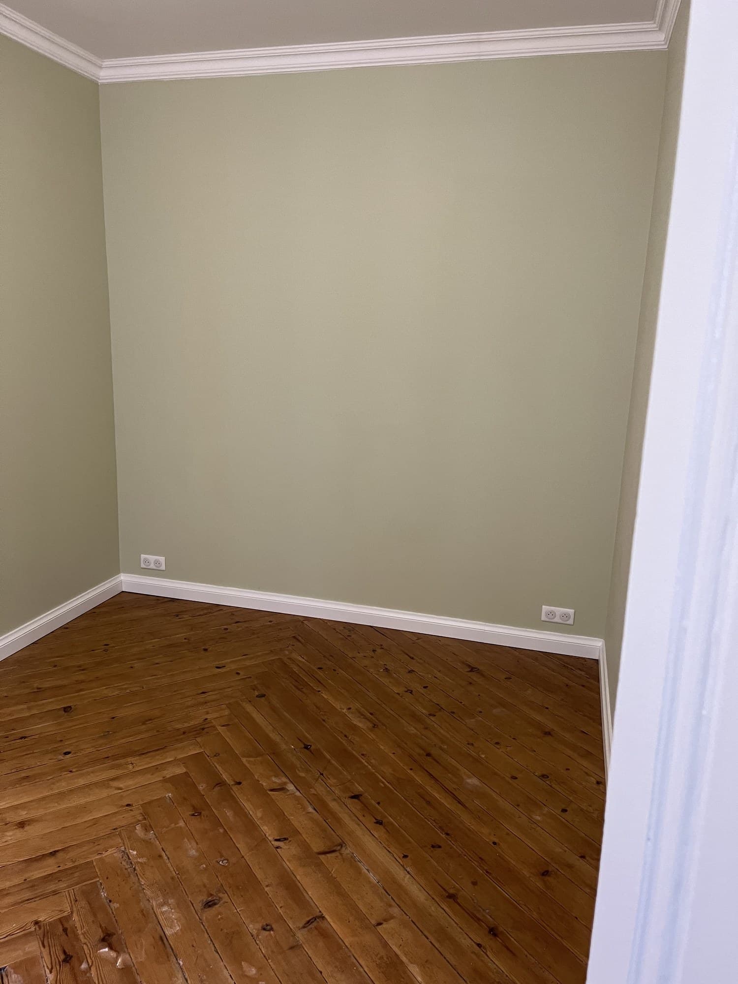 Chambre après travaux : murs vert sauge mat, corniches et plinthes blanches, parquet ancien dégagé