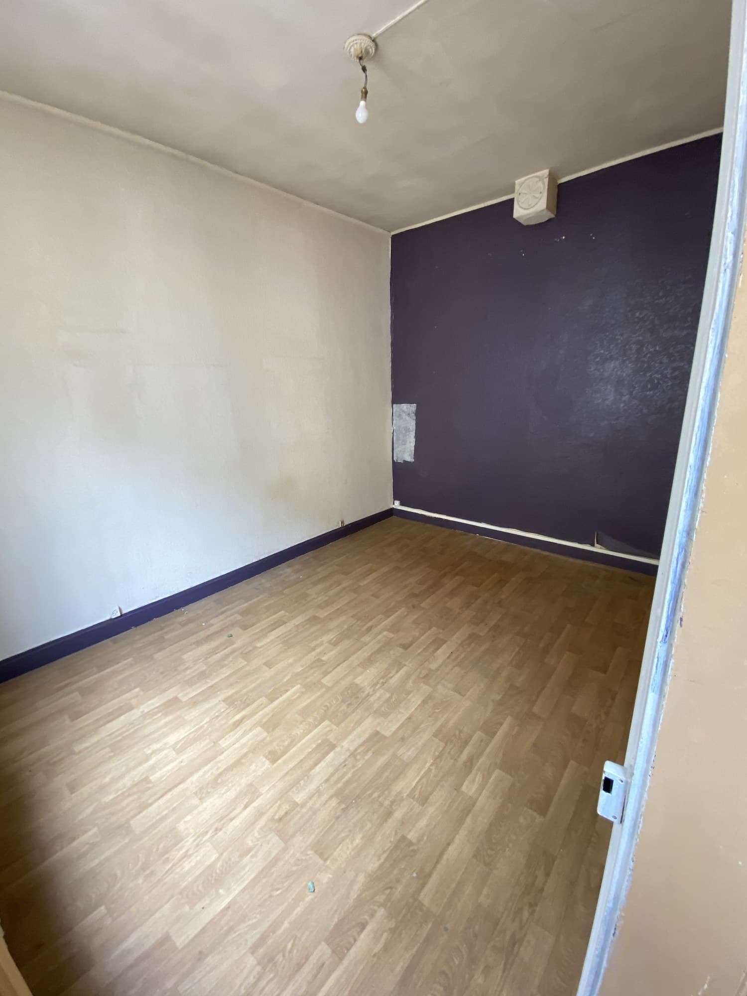 Chambre avant travaux : mur aubergine, plinthes violettes, sol en lino imitation bois